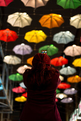 Fototapeta na wymiar unrecognizable woman from behind taking photo of colored umbrella in the street