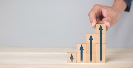 Growth graph and arrows ladder career path for business growth success process concept.Hand arranging wood block stacking as step stair with arrow up. © kunakorn