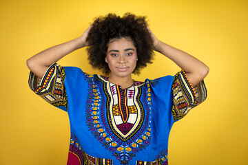 African american woman wearing african clothing over yellow background with a happy face standing and smiling with a confident smile showing teeth