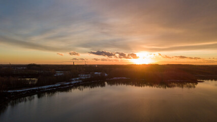 Aerial view of a beautiful and dramatic sunset over a forest lake reflected in the water, landscape drone shot. Blakheide, Beerse, Belgium. High quality photo