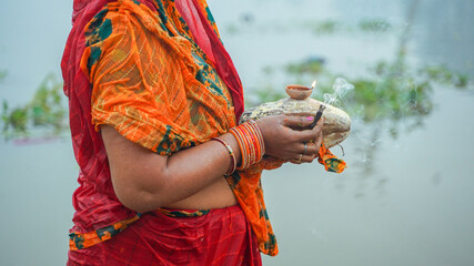 Woman celebrating chhath puja and holding fruits in hand