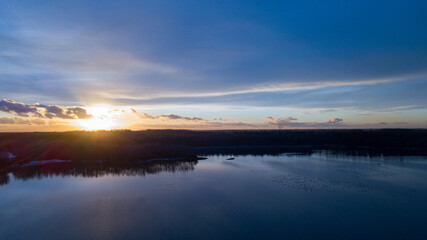 Aerial view of a beautiful and dramatic sunset over a forest lake reflected in the water, landscape drone shot. Blakheide, Beerse, Belgium. High quality photo