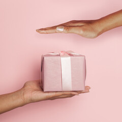 Hand with gift on pink card background