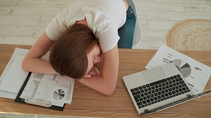Young tired woman sleeping at her office desk near the laptop