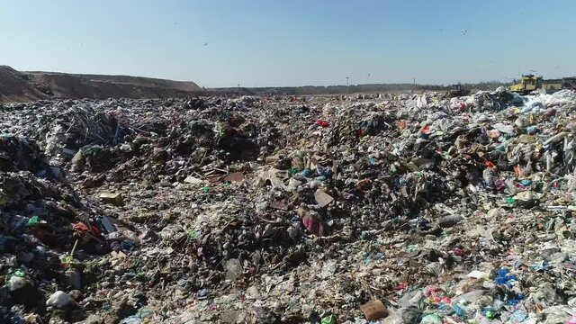 Open city garbage dump. Birds are flying, a bulldozer is leveling piles of waste, aerial photography. Concept: environmental problems of the city, environmental pollution, landfill for waste disposal.
