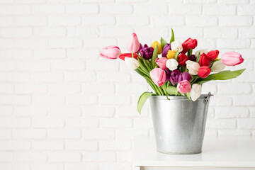 Bucket of tulip flowers over white brick wall background