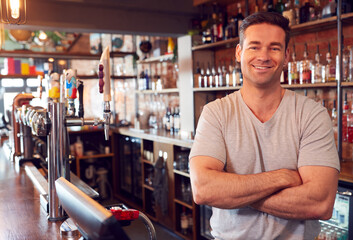 Portrait Of Smiling Male Bar Owner Standing Behind Counter