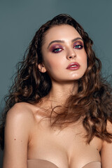 A brooding beautiful model woman with chic natural curly hair. Shiny silk hair. Evening make-up.