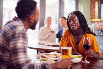 Smiling Young Couple On Date Enjoying Pizza In Restaurant Together