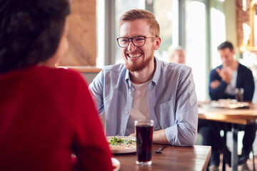 Smiling Young Couple On Date Enjoying Pizza In Restaurant Together