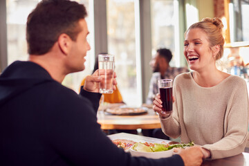 Smiling Couple On Date Enjoying Pizza In Restaurant Together