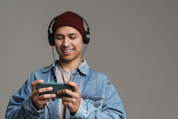 Joyful handsome guy listening music with headphones and cellphone