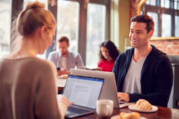 Business Couple With Laptops Having Informal Meeting In Coffee Shop