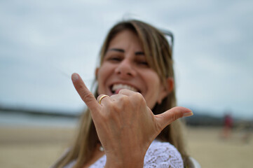 Portrait of a beautiful woman doing hang loose on the beach