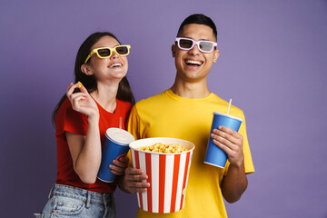 Joyful couple in 3d glasses eating popcorn while watching movie