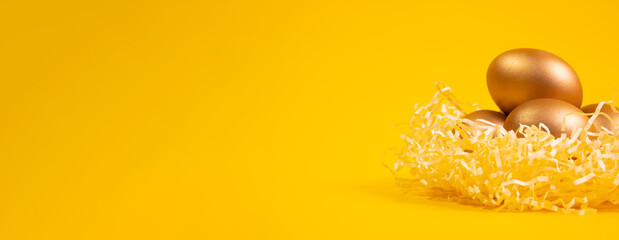 Easter background with colorful eggs in nest oon a yellow background. Top view with copy space. Banner.