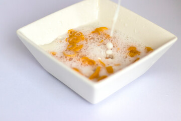 Milk being poured in to the white bowl with cereal in it. Food