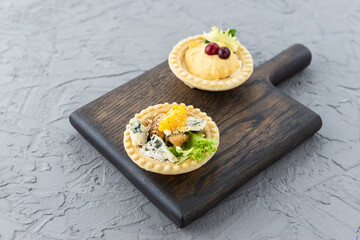 Tartlets with mussels, blue cheese, orange and pate on a wooden board.