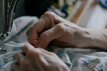 closeup of sewing on vintage sewing machine with senior female hands. selective focus photo