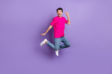 Fototapeta na wymiar Full size photo of young happy cheerful excited smiling man jumping showing v-sign isolated on purple color background