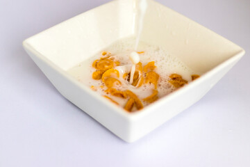 Milk being poured in to the white bowl with cereal in it. Food