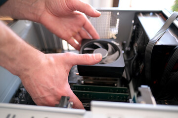 Fototapeta na wymiar hands of young male master install cooler with copper heat pipes for the processor, other parts of pc into case, the concept of repairing equipment, assembling, upgrading a personal computer
