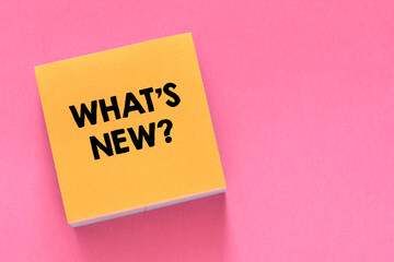 WHAT'S NEW? text written on a small yellow piece of paper and a pink background.