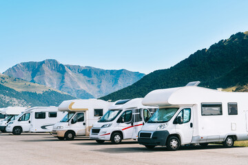 Summer tourism with rv in the mountain. Campers parked in a row in a caravan parking area. Best option for travel feeling free. Motorhomes and campingcar. - obrazy, fototapety, plakaty