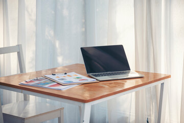 Office laptop business financial document chart and graph on wooden table with coffee cup. Flat lay notebook computer laptop on office desk. No people business graph chart mockup on business workspace