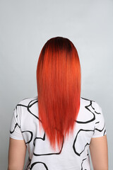 Woman with bright dyed hair on grey background, back view
