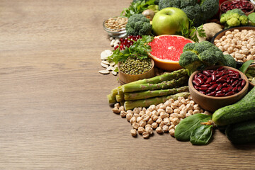 Fresh vegetables, fruits and seeds on wooden table, space for text
