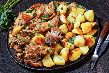 braised Rabbit with potatoes on a black plate
