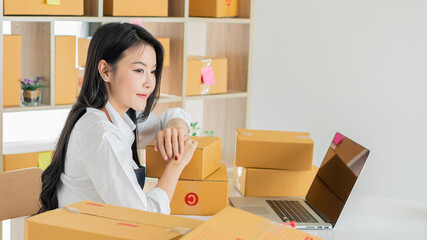 Small Business Startup Freelance SME Entrepreneurs Beautiful Asian Young Women Working at Home with Box, Smartphone, Laptop on the Table with Online Sales, Marketing, Packaging, SME Shipping, Ecommerc