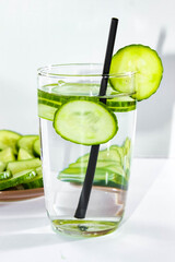 Detox water with sliced cucumber in a glass with a straw for drinking. The concept of losing weight and cleansing the body.