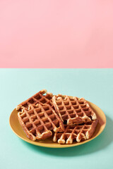 Time for delicious dessert. Vertical shot of freshly baked Belgian waffles with sugar on yellow plate