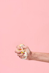 Say no to unhealthy food. Hand squeezing, smashing donut on pink background