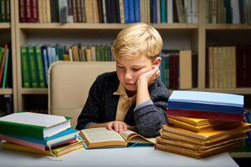 child boy under mental pressure while reading books preparing examinations, in library .