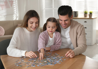 Fototapeta premium Happy family playing with puzzles at home