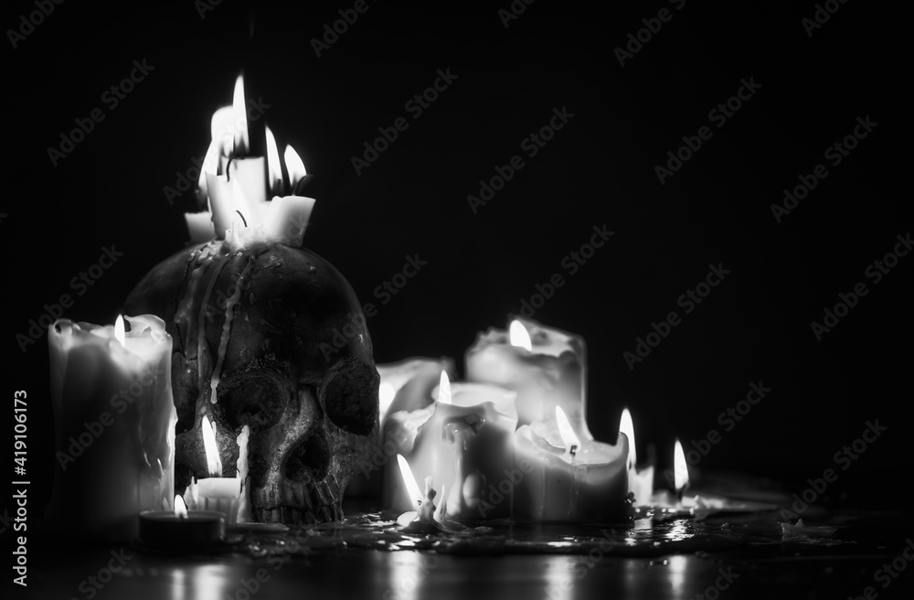 Wall mural Candles and human skull in darkness closeup in black and whiter