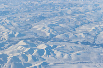 Aerial view of snow-capped mountains. Winter snowy mountain landscape. Icheghem Range, Kolyma Mountains. Koryak Okrug (Koryakia), Kamchatka Krai, Siberia, Far East of Russia. Great for backgrounds.