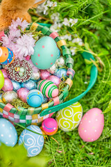 Fototapeta na wymiar Easter greeting card with sweet snack basket, easter basket with sweets and chocolate eggs hidden in nature by the easter bunny.