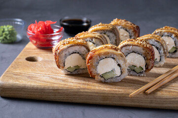 Sushi set with smoked eel and philadelphia cheese on wooden board on gray background. Healthy food.