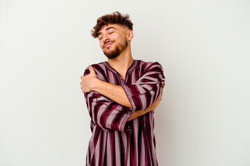 Young Moroccan man isolated on white background hugs, smiling carefree and happy.