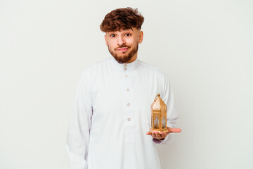 Young Moroccan man wearing a typical arab clothes holding a ramadan lamp isolated on white background confused, feels doubtful and unsure.