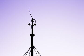 Weather station in silhouette over the sky at sunset