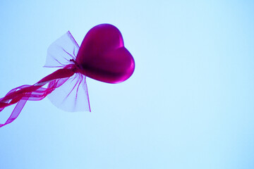 Red heart attached to a stick with a bow hanging