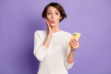 Photo portrait of girl with bob hair amazed shocked touching cheekbone keeping smartphone isolated on vivid violet color background