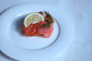Sandwich of salty salmon slices with lemon and dill on white plate