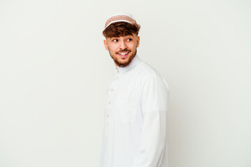 Young Arab man wearing the typical arabic costume isolated on white background looks aside smiling, cheerful and pleasant.