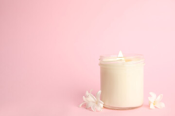Beautiful candle with wooden wick and flowers on pink background, space for text